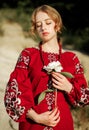 The girl in a traditional ethnic red dress posing outdoors with a white peony flower in her hand Royalty Free Stock Photo