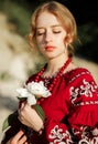The girl in a traditional ethnic red dress posing outdoors with a white peony flower in her hand Royalty Free Stock Photo