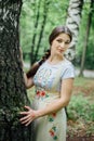 Girl in traditional Russian dress sarafan leaned against birch Royalty Free Stock Photo