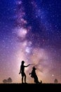 Girl trains dog at park. Woman and pet outline. Milky Way at night sky Royalty Free Stock Photo