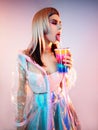 Girl in transparent cloak holding colorful shaker and drinking cocktail