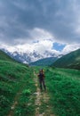 Girl traveler with a backpack in the mountains of Georgia. North Caucasus. Walking route to the village of Ushguli. Green valley Royalty Free Stock Photo