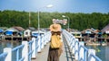 Girl traveler with backpack walking over bridge on the lake Tourism in rural villages Ban Bang Phat - Phangnga. Asian woman travel