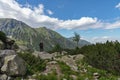 Girl traveler in black jacket with backpack standing near the top of the mountais, amazing panorama, active life concept