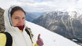 Girl traveler brunette takes a selfie and shows a thumb up against the mountains. Travel with a backpack