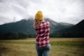 Girl traveler in hat with backpack looking at clouds in mountains