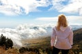 Girl is a traveler in a mountain trek. A view from above on mountains and clouds. Above the clouds