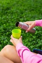 Girl traveler pours tea from a thermos, on the street. A woman pours a hot drink into a mug from a thermos.