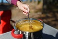 Girl traveler prepares food on portable gas stove, on a folding table on the background of camping in forest. Women's hands inter Royalty Free Stock Photo