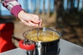 Girl traveler prepares food on portable gas stove, on a folding table on the background of camping in forest. Women's hands inter Royalty Free Stock Photo