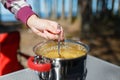 Girl traveler prepares food on portable gas stove, on a folding table on the background of camping in forest. Women's hands inter Royalty Free Stock Photo