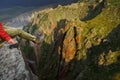 Girl traveler sits on the edge of a cliff. Female feet in the ba