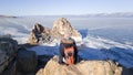 Girl traveler sitting on Cape Burhan and admires the rock Shaman on the island of Olkhon in Russia. Backpack over shoulders.