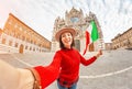 girl travels in Italy. Happy young hipster woman posing with flag in front of the Duomo Cathedral in Siena. Vacation and Royalty Free Stock Photo