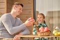 Girl treating apple to man sitting at table