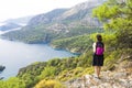 A girl on a trekking trip in the mountains, admires the beautiful natural view of the bay of the sea and the mountains of the