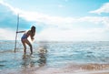 Girl with a trident in his hand looks at the sea surface