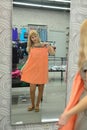 Girl tries on a new dress in the shop front of a mirror Royalty Free Stock Photo