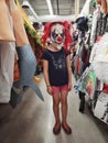 Girl trying on costume spooky scary creepy clown mask in store for Halloween holiday celebration