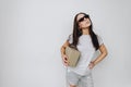 The girl turned up her nose with box in her hands. Girl with glasses on background of white wall