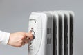 The girl turns on the heater on grey background, side view Royalty Free Stock Photo