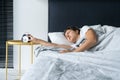 The girl turns off the annoying alarm clock to continue sleeping. Get some more sleep. It a hard morning. Time to wake up Royalty Free Stock Photo