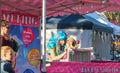 Girl in turqoise wig painting a girls face in face painting booth wth mother and sister looking on in Redlands Queensland Aus