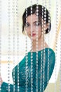 Girl in a turquoise dress standing behind decorative glass curtain. Focus on creeping stones. The girl is blurred Royalty Free Stock Photo