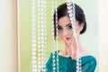 Girl in a turquoise dress standing behind decorative glass curtain. Focus on girl`s hand. The girl is blurred Royalty Free Stock Photo