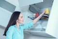 Girl in a turquoise shirt puts a yellow Cup on the drying shelf of the kitchen cupboard