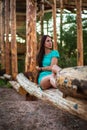 Girl in turquoise short dress sitting on a tree log