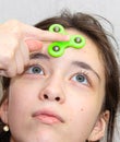 The girl twists the fidget spinner stress relief toy on her forehead