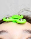 The girl twists the fidget spinner stress relief toy on her forehead
