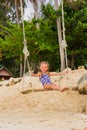 Girl with two braids in a bathing suit on a swing on the beach Royalty Free Stock Photo