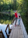 A girl with two children are standing on the old wooden bridge across a quiet river Royalty Free Stock Photo