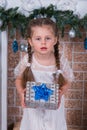 Girl with two pigtails with a gift in a box in the New Years holiday