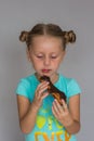 The girl with two plaits biting a chocolate cake Royalty Free Stock Photo