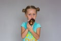 The girl with two plaits biting a chocolate cake Royalty Free Stock Photo