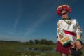 A girl in Ukrainian embroidery with a wreath on her head by the lake in a meadow among the flowers