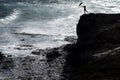 Girl with umbrella leans over a high cliff on the rough sea