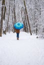 Girl under blue umbrella in snowy forest. Snowfall concept. Woman under wet snow rain in winter park. Royalty Free Stock Photo