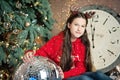 Girl under christmas tree waiting for the new year near disco ball decoration. Royalty Free Stock Photo