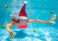 Girl underwater in Santa hat with Christmas balls Royalty Free Stock Photo