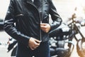 Girl unfastens black leather jacket on background motorcycle in sun flare atmospheric city, hipster biker female hands closeup Royalty Free Stock Photo