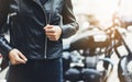 Girl unfastens black leather jacket on background motorcycle in sun flare atmospheric city, hipster biker female hands closeup Royalty Free Stock Photo