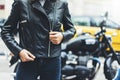 Girl unfastens black leather jacket on background motorcycle taxi in sun flare atmospheric city, hipster biker female hands Royalty Free Stock Photo