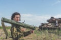 Girl in uniform with a Bazooka on the background of a broken tan