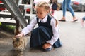 Girl in uniform stroking stray cat on street, in first time goes to school Royalty Free Stock Photo