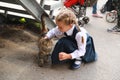 Girl in uniform stroking stray cat on street, in first time goes to school Royalty Free Stock Photo