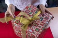 The girl unties the bow on the gift box. The concept of the new year holiday